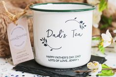 a white coffee mug with the words dad's tea on it next to some flowers