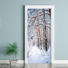 an open door with a snowy forest scene in the background and a potted plant next to it