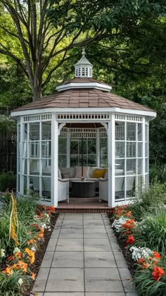 a white gazebo surrounded by flowers and trees