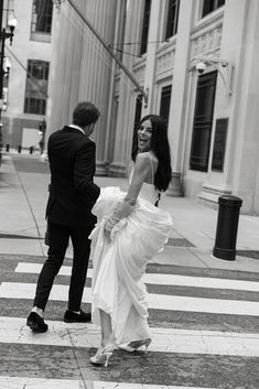 a man in a tuxedo is walking with a woman across the crosswalk