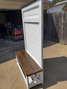 a wooden bench sitting next to a white shed