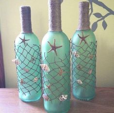 three green bottles with sea shells and starfish on them sitting on a wooden table