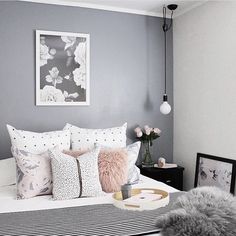 a bed with white and pink pillows on top of it next to a black table