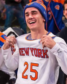 a man in a new york jersey is smiling and holding up his jersey with the number 25 on it