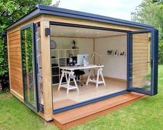 a small backyard office in the middle of a yard with an outside dining table and chairs