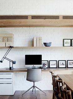 a home office with white brick walls and wooden shelves