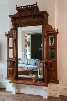 a large mirror sitting on top of a wooden shelf next to a couch and coffee table