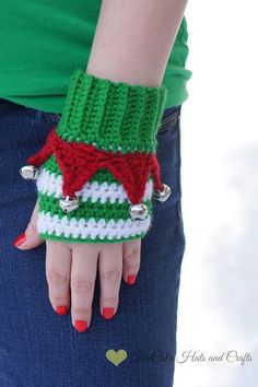 a woman's hand wearing a green and white knitted wrist warmer with bells