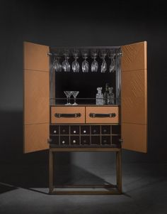 an open cabinet with wine glasses on top and bottles in the bottom drawer, sitting against a black background