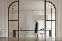 an open door leading to a kitchen with marble counter tops and white cabinets, along with a person standing in the doorway