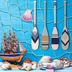 there are many paddles on the wall next to some shells and seashells