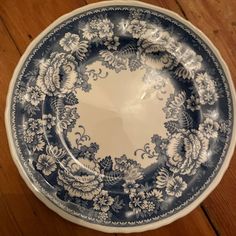 a blue and white plate sitting on top of a wooden floor next to a wall