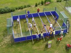 an aerial view of people playing tennis on the grass in front of a blue fence