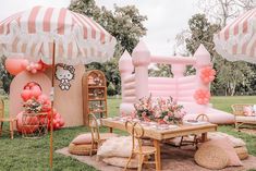 a hello kitty themed birthday party with pink and white balloons, table set up in the grass