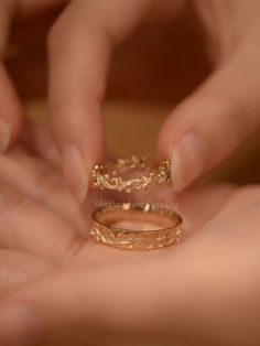 two hands holding gold wedding rings on top of each other's fingers, with the ring being held by another hand