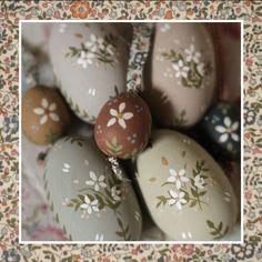 several decorated eggs sitting on top of a floral cloth covered tablecloth with flowers and leaves