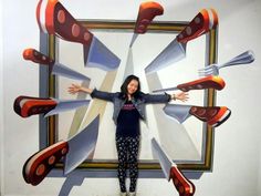 a woman standing in front of a painting with forks sticking out of it's arms