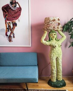 a living room with a blue couch and pink walls holding up a large piece of art