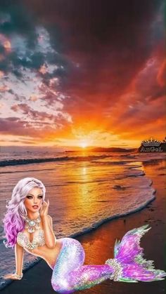 a mermaid sitting on top of a beach next to the ocean