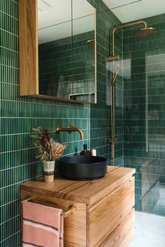 a bathroom with green tiled walls and wooden vanity