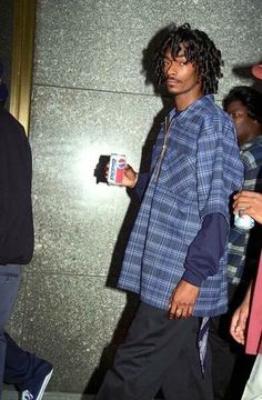 a young man walking down the street with his cell phone in one hand and an ipod in another