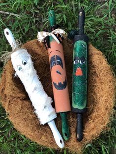 three different types of toothbrushes with faces painted on them sitting in the grass