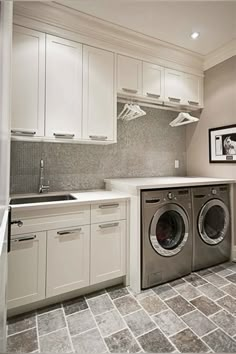 a washer and dryer in a small room with white cabinets on the walls