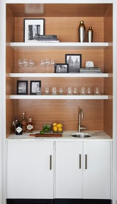 a kitchen with white cabinets and shelves filled with wine glasses