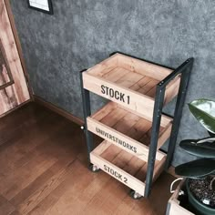 a wooden shelf sitting next to a potted plant on top of a hard wood floor