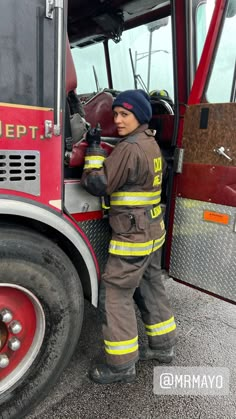 a firefighter is standing next to the door of a fire truck and holding his hand out