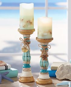 two candles sitting on top of a table next to a starfish and seashell