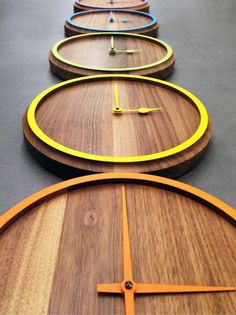 four wooden clocks with different colors on them