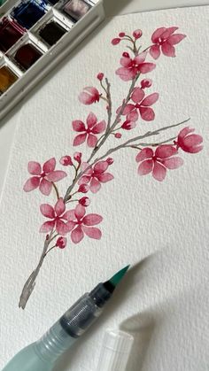 a watercolor painting of pink flowers on white paper next to a marker and paintbrush