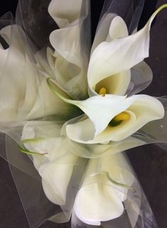 white flowers are in a clear vase on a black tableclothed surface and the center piece is visible from above