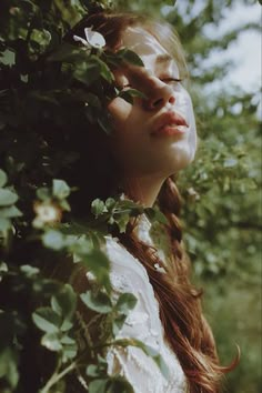 a woman with her eyes closed standing in the woods