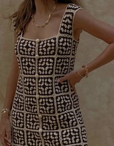 a woman in a black and white dress posing with her hands on her hips while wearing gold jewelry