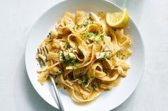 a white plate topped with pasta and lemon wedges