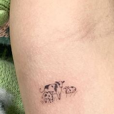 a small tattoo on the leg of a man with cows drawn on it's side