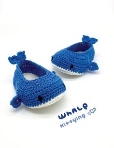 two blue crocheted baby shoes sitting on top of a white table next to each other