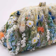 a close up of a bag made out of beads and flowers on a white surface