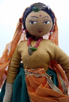 a cloth doll with an orange scarf around it's neck and headdress