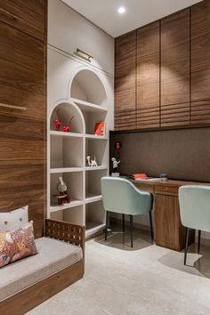 a room with two chairs, a desk and shelves filled with bookshelves next to each other