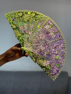 a person holding an umbrella with green and purple designs on it's outside,