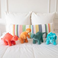 three stuffed animals sitting on top of a bed next to two pillows and a pillow