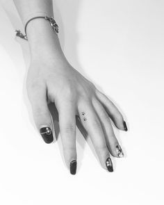 a woman's hand with black and white nail polish holding onto her bracelets