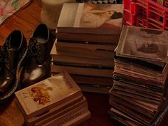 a pile of books sitting on top of a wooden floor next to a stack of shoes