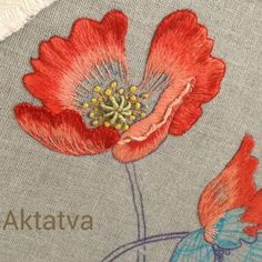 a red flower is embroidered on the back of a gray shirt with blue and white trim