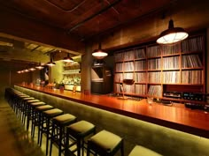 an empty bar with lots of stools in front of it and shelves full of records