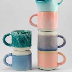 three different colored coffee mugs stacked on top of each other