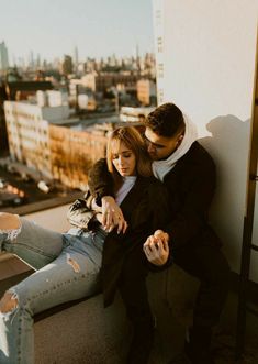 a man and woman sitting next to each other on top of a building